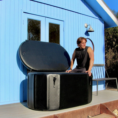 A person shoulder-deep in a portable inflatable cold plunge in a backyard