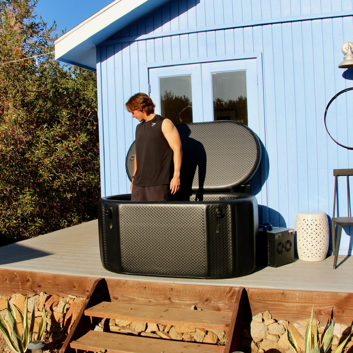A person standing inside the 98 gallon inflatable ice bath tub, showing its depth and rigid drop-stitch walls